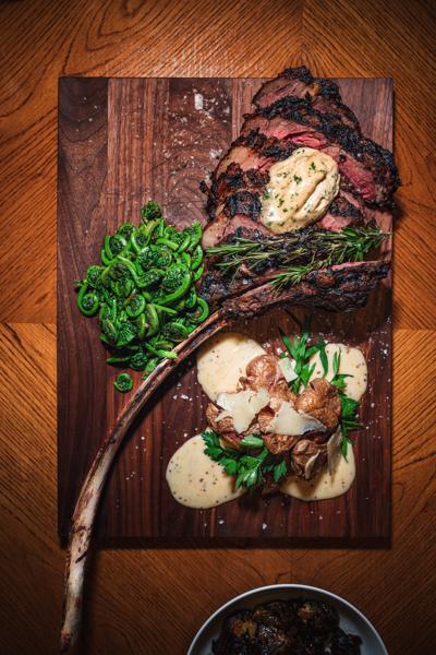 A steak and fiddleheads meal on a cutting board in Vermont.
