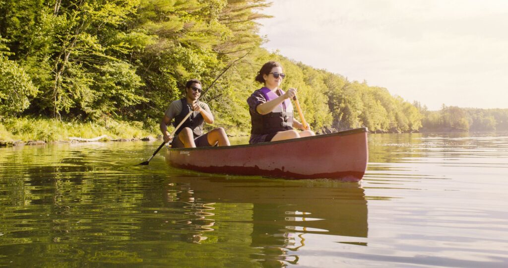 Two people paddle a canoe on a reservoir in Vermont.
