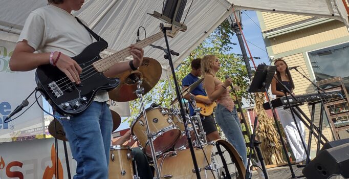 A rock band performs on an outdoor stage.