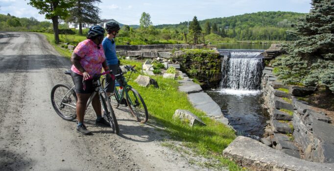 Two cyclists stop to look at a waterfall in Vermont.