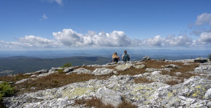 Two people sit on a rocky mountaintop in Vermont.