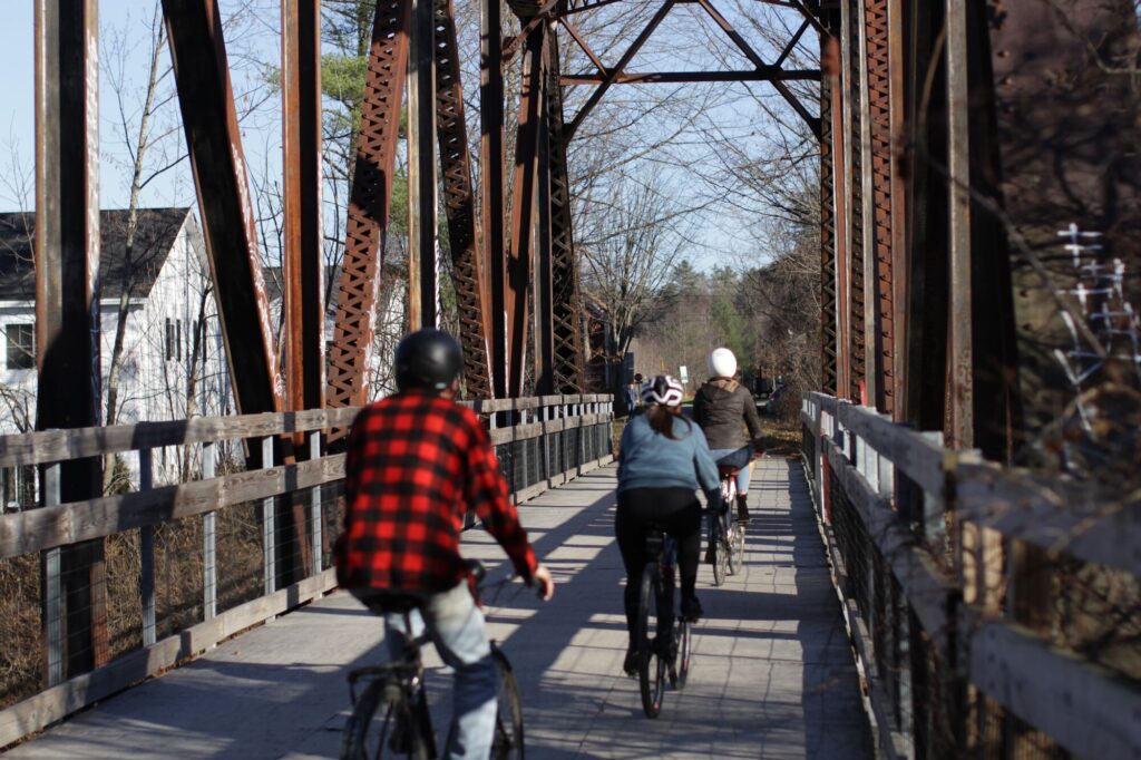Three cyclists ride across an old railroad bridge in Vermont.