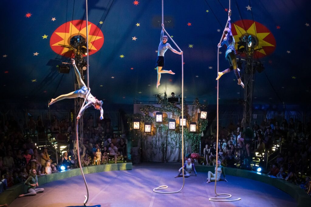 Three circus performers dancing high in the air on ropes.