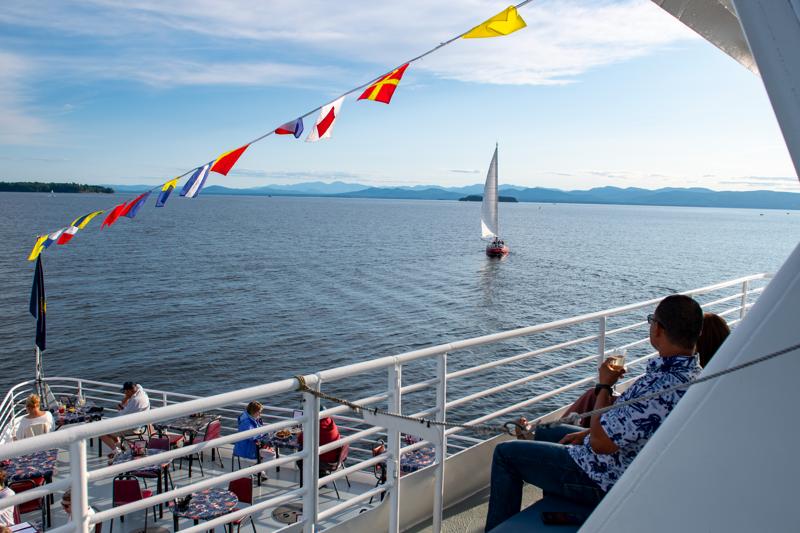 People sit on the deck of a large tour boat on Lake Champlain in Vermont.