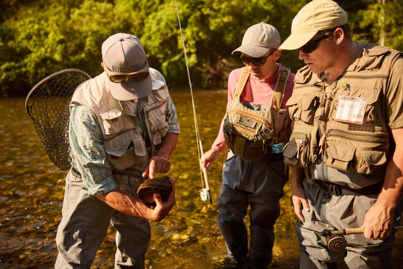 Three people fishing in a river in Vermont.