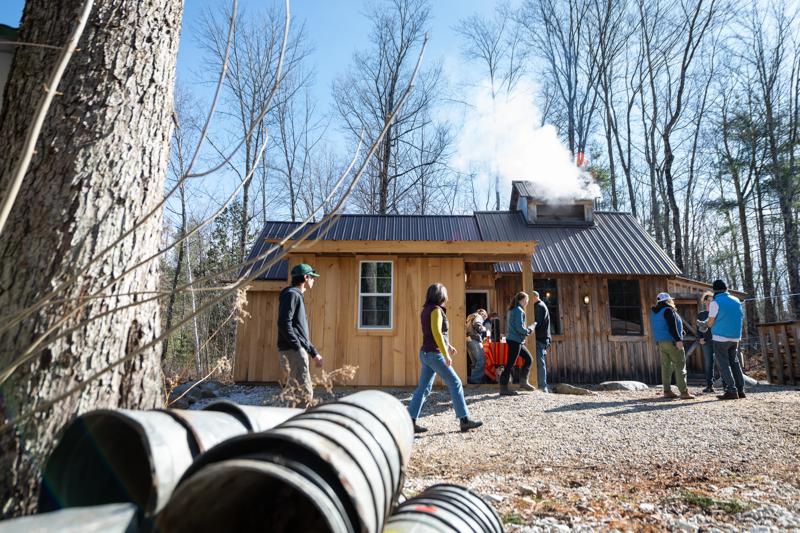 People walk around the outside of a maple sugarhouse in Vermont.