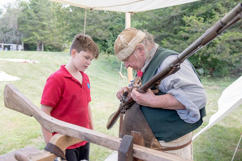 A historian shows an American Revolution musket to a young person.