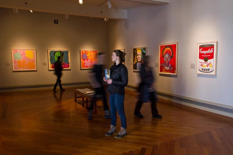 Visitors admiring an exhibition of screenprints inside the Middlebury College Museum of Art gallery.