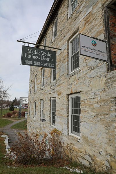 Exterior of a historic stone building in the Marble Works Business District of Middlebury, Vermont, featuring business signage.