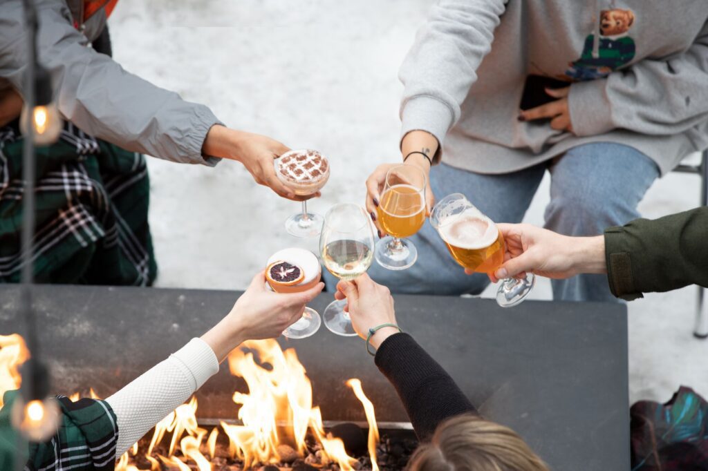 Hands holding drinks seen from above fireside in the winter.