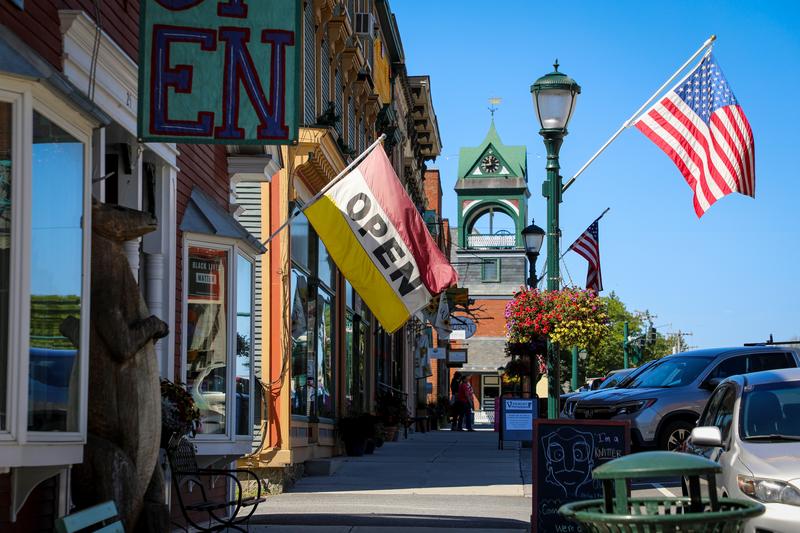A row of local storefronts in Bristol, Vermont, featuring an Open and American flag.