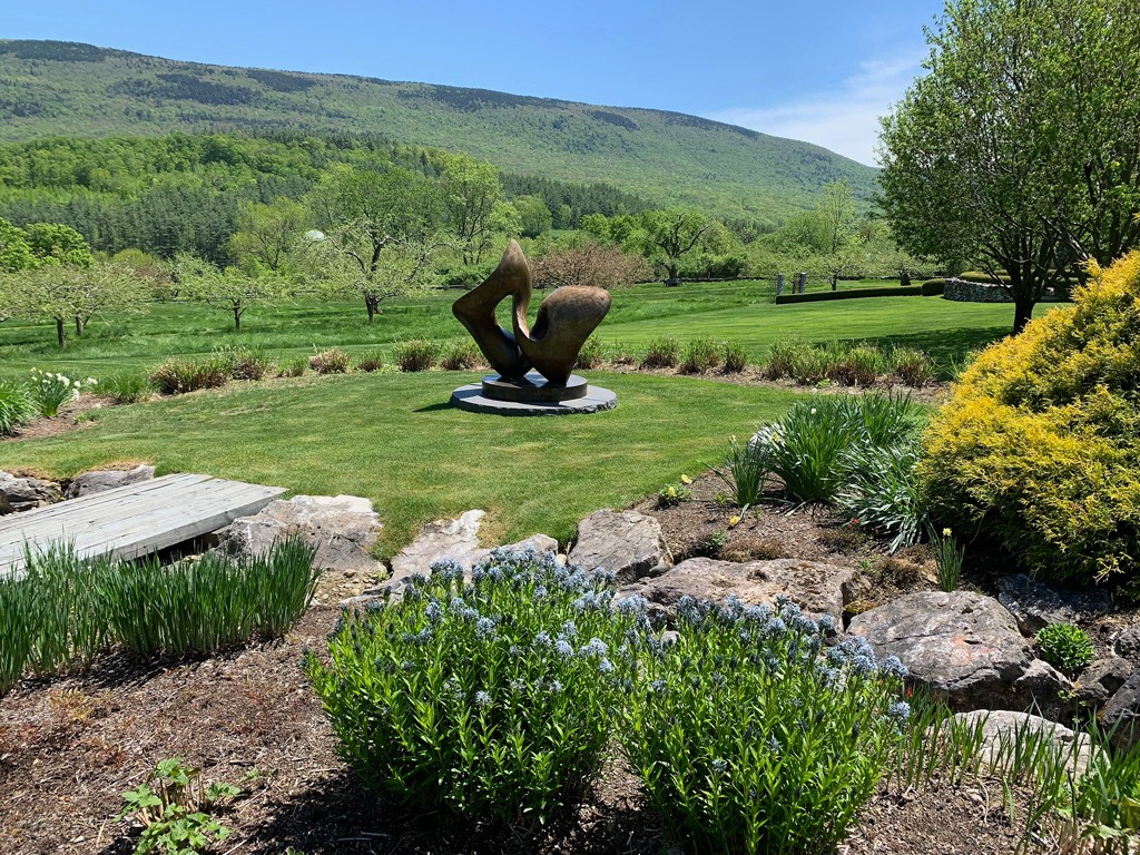 Sculpture in a Seven Springs garden with green mountain arching in the background.